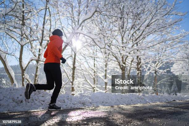 Side View Woman Jogging Running On Road Cold Sunny Winter Day Stock Photo - Download Image Now