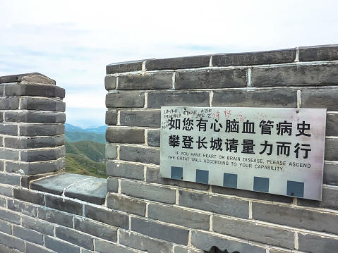 BEIJING, CHINA – October 14, 2013: fragment of Great Wall of China wall with a warning sign in Chinese and English near Beijing, China