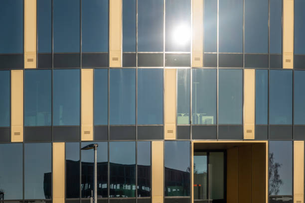 riflesso del sole su un edificio moderno con una facciata di vetro e cemento - puritanical foto e immagini stock