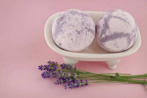 istock Lavender Bath Bombs.purple bath bombs and lavender flowers in a ceramic bath on a light pink background.Pure organic body cosmetics with lavender extract 1075899810