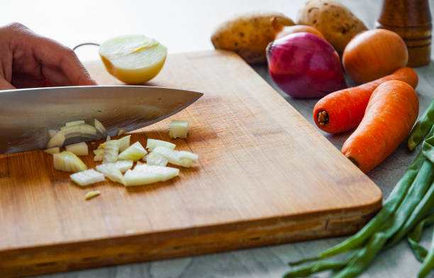 istock Chefs hands with knife chopping vegetables on wooden board 1075904202