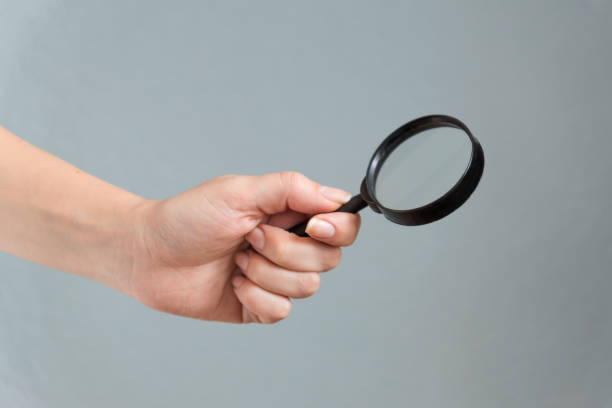 istock wooman hand holding magnifyer glass on gray background 1075904240