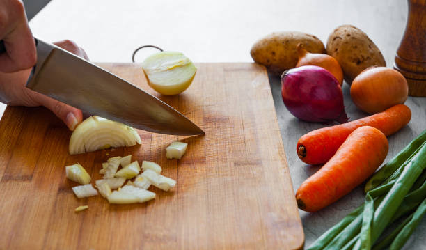 istock Chefs hands with knife chopping vegetables on wooden board 1075904270