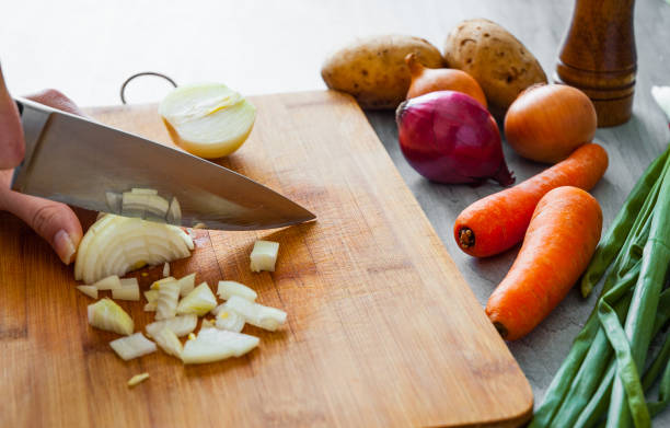 istock Chefs hands with knife chopping vegetables on wooden board 1075904276