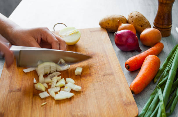 istock Chefs hands with knife chopping vegetables on wooden board 1075906354