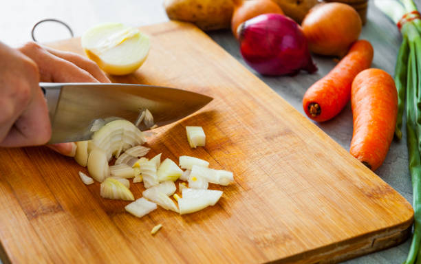 istock Chefs hands with knife chopping vegetables on wooden board 1075906488