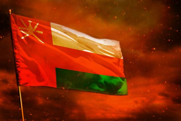 istock Fluttering Oman flag on crimson red sky with smoke pillars background. Troubles concept. 1075908164