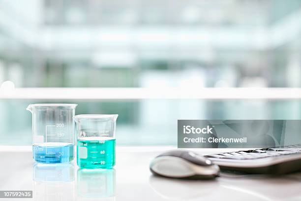 Foto de Beakers Com Computador Teclado E Mouse Sobre Uma Escrivaninha e mais fotos de stock de Ausência