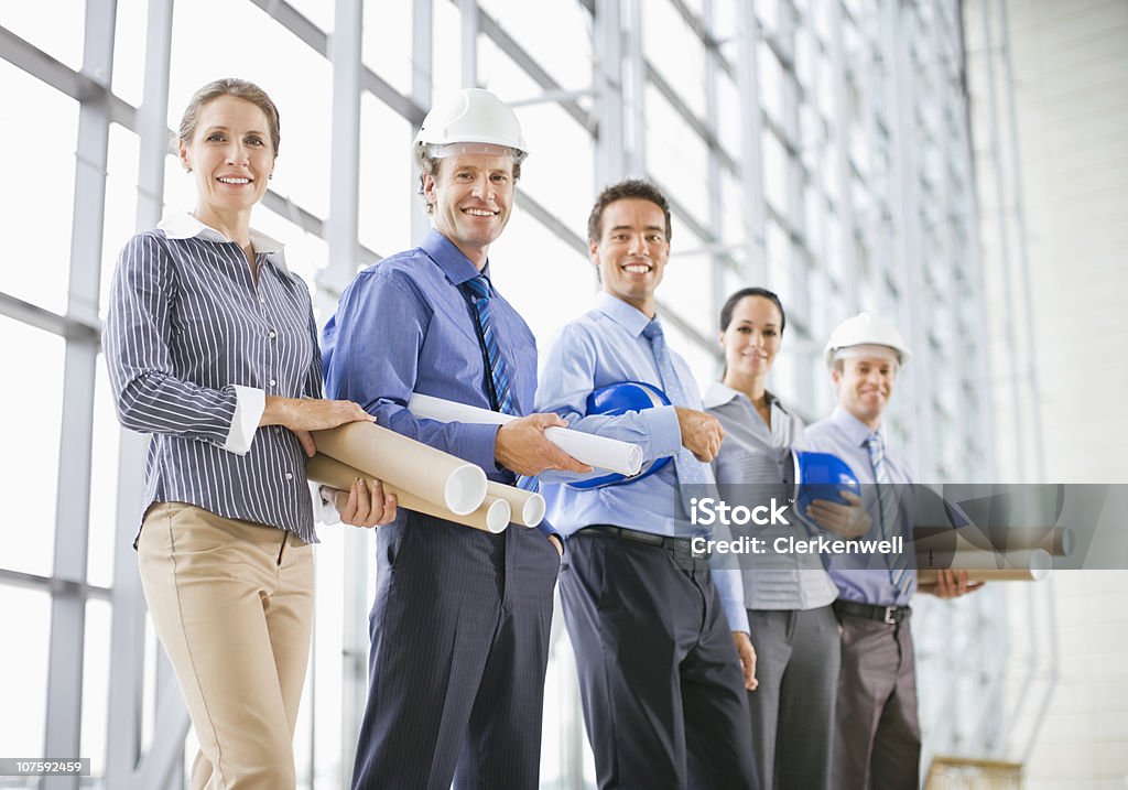 Retrato de grupo de homens e mulheres arquitetos com hardhats e b - Foto de stock de 25-30 Anos royalty-free