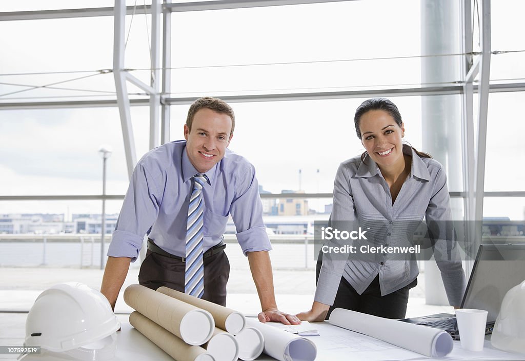 Portrait of a happy male and female architects with blue prints at office  Architect Stock Photo