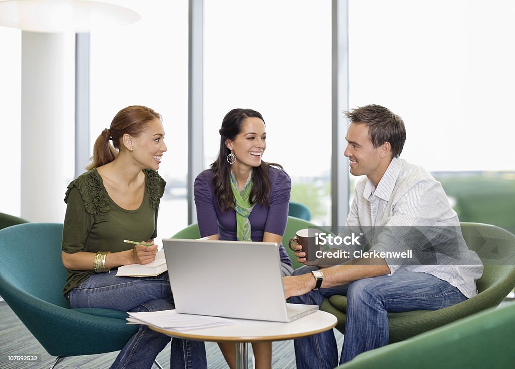 Sus colegas de oficina feliz sentado en la oficina y estuche portátil - Foto de stock de 25-29 años libre de derechos