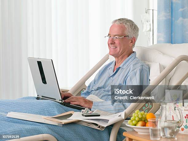 Foto de Sorrindo Paciente Sênior Na Cama Usando Laptop No Hospital e mais fotos de stock de Cama