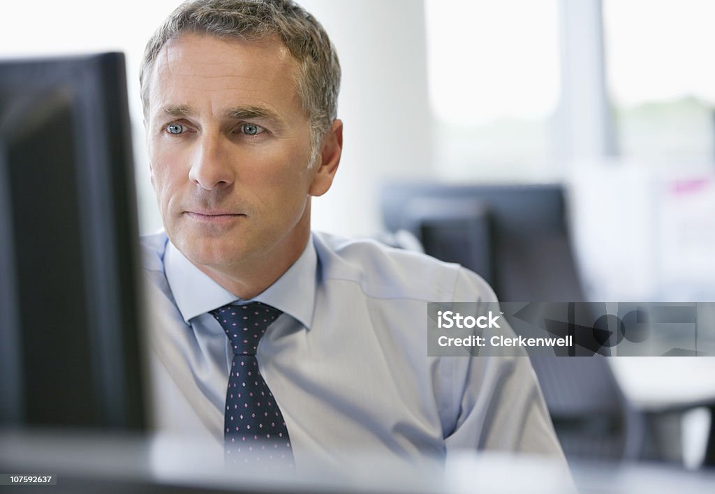 Mature business executive looking at computer screen at office  45-49 Years Stock Photo