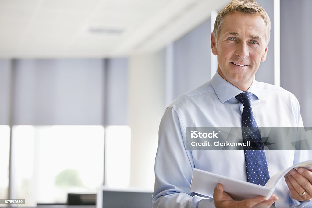 Portrait of a mature businessman with document at office, smiling  45-49 Years Stock Photo