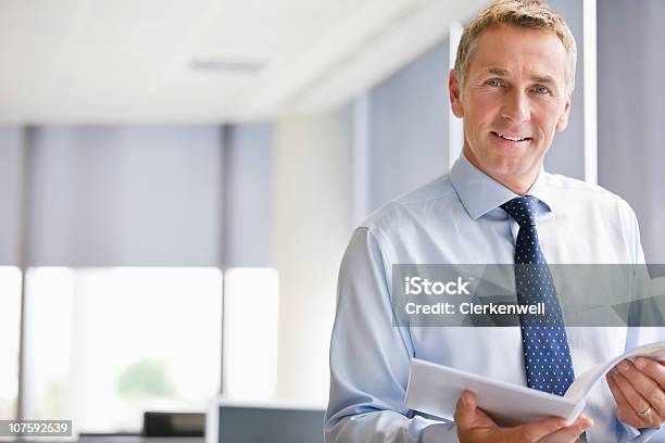 Portrait Of A Mature Businessman With Document At Office Smiling Stock Photo - Download Image Now