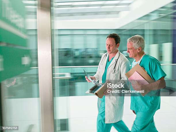 Zwei Ärzte Mit Peelings Zu Fuß In Eile In Hospital Stockfoto und mehr Bilder von 30-34 Jahre - 30-34 Jahre, 60-64 Jahre, Alter Erwachsener