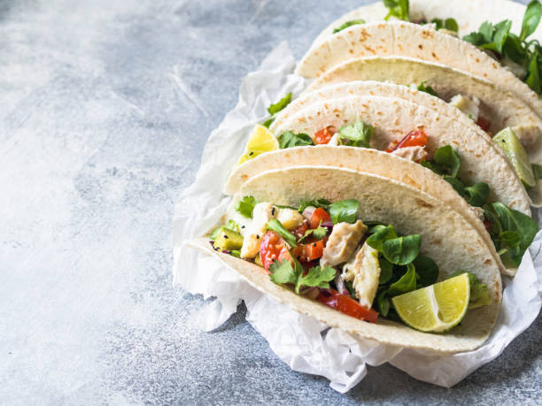 istock Tortillas with vegetables and white fish. Avocados, tomatoes, red onions and cod pieces sprinkled with sesame and lime juice in tortillas. Mexican food. Copy space 1075927894