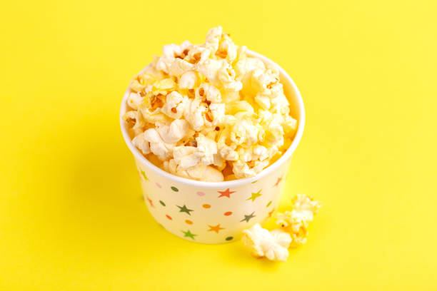 istock Tasty salty popcorn in paper cup on bright yellow background 1075936068