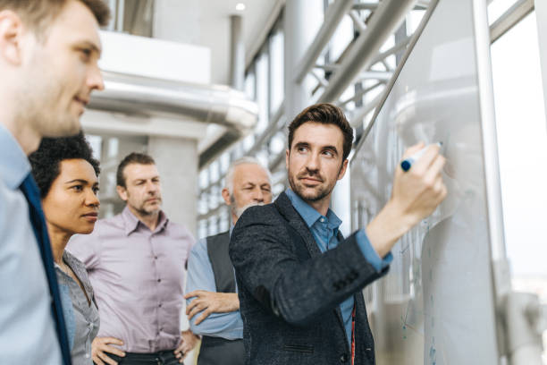 istock Young entrepreneur talking to his colleagues while drawing business development on whiteboard. 1075951088
