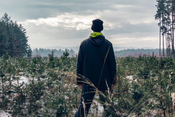 istock Young man standing in winter in forest with snow and dramatic sky 1075955744