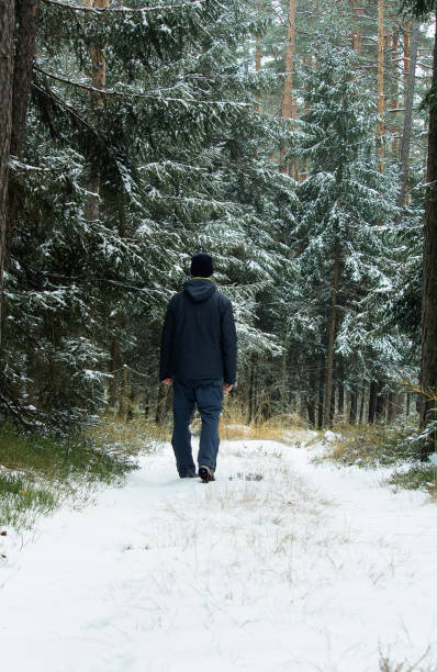 istock Young man standing in winter landscape in forest with snow 1075955864