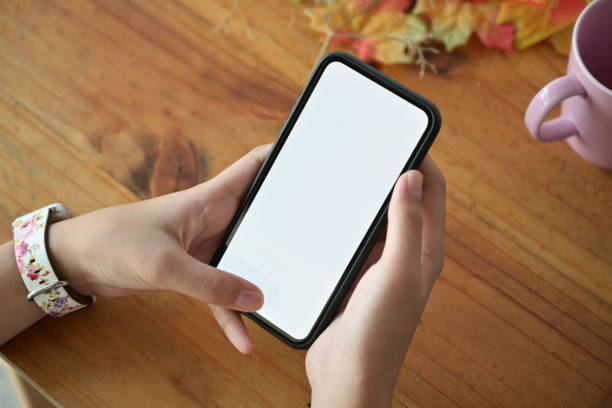 istock Top view of women's hands holding mobile phone with blank screen for graphics display montage. 1075965778