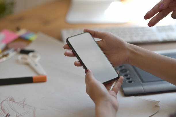 istock Stylish fashion designer using mobile phone in atelier. 1075969616