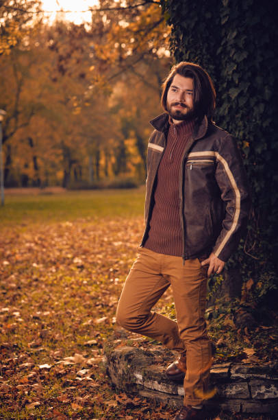 Man posing near tree in autumn colored park.