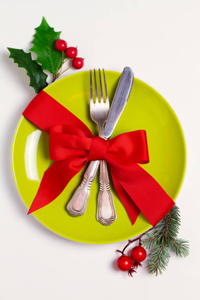 istock Christmas composition with plate, cutlery, pine branches, ribbon and red berries on white table. Winter holidays and festive background 1075978024