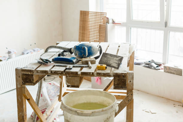 istock Construction grunge ladder, paint roller and paint bucket in white interior: white wall and gray floor. Apartment decoration concept. 1075979030
