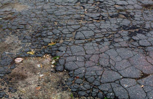 Old aged grey cracked asphalt road surface stock photo