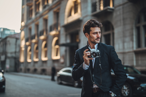 Handsome guy using camera on the street looking over his shoulder