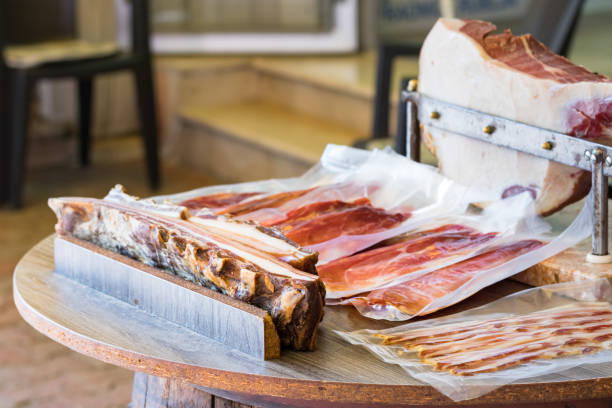 wooden table with raw ham sliced packed with ham leg in the background. - leg split imagens e fotografias de stock