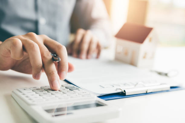 agentes están utilizando una calculadora para calcular el período del préstamo cada mes para el cliente. - inmobiliaria fotografías e imágenes de stock