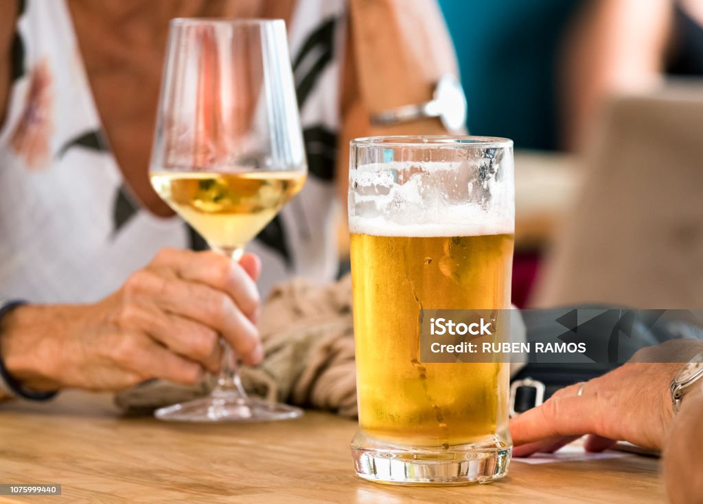 Hands of a couple having beer and white wine sitting in a table outdoors a bar in Spli, Croatia. Hands of a couple having beer and white wine sitting in a table outdoors a bar in Split, Croatia. Beer - Alcohol Stock Photo