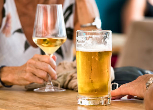 Hands of a couple having beer and white wine sitting in a table outdoors a bar in Spli, Croatia. stock photo
