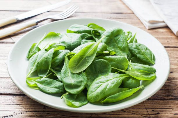 istock Fresh spinach leaves in bowl on rustic wooden table. 1076008734