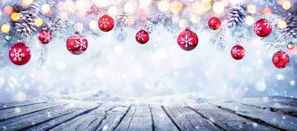 Photo of Christmas Table With Red Hanging Balls In Snowy Background