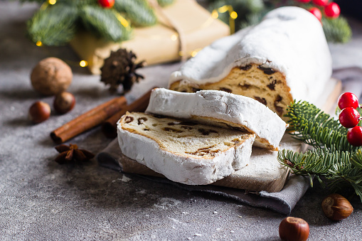 Traditional Christmas festive pastry dessert with festive decoration. Christmas stollen on wooden background. Top view, copy space
