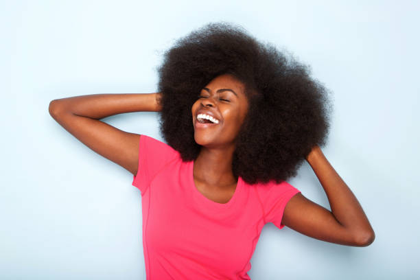 cheerful young black woman with hands behind head Close up portrait of cheerful young black woman with hands behind head natural hair stock pictures, royalty-free photos & images