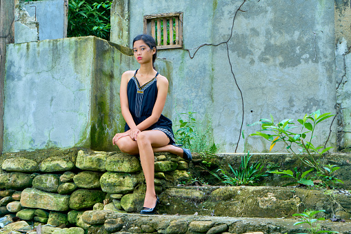 Beautiful woman posing - sitting on the abandoned staircase , hands on knee, looking at camera