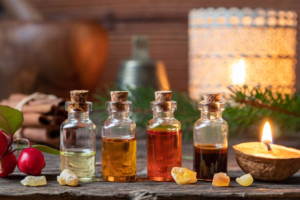 christmas collection of essential oils with frankincense, wintergreen and candles - aromatic oil imagens e fotografias de stock