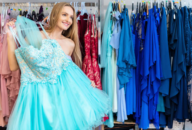 Woman decided to buy blue dress Smiling woman shopping at clothing store and trying on elegant blue prom dress. Woman decided to buy this luxury evening gown. prom dress stock pictures, royalty-free photos & images