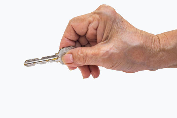 istock Senior woman's right hand holding key isolated on white background 1076050940