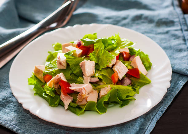istock fresh vegetables salad with chicken and onion, lettuce, tomato in white plate on table 1076054980