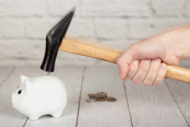 istock A hand with hammer breaking the piggy bank 1076058276