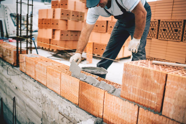 istock Bricklayer industrial worker installing brick masonry on exterior wall with trowel putty knife 1076060484