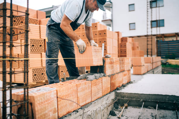 istock closeup of construction worker installing bricks, building house 1076060548