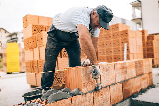 trabajador industrial construcción de paredes exteriores, usando el martillo para la colocación de ladrillos de cemento. Detalle del trabajador con herramientas y hormigón photo