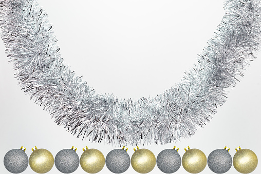 Hanging silver tinsel with silver and yellow Christmas baubles, isolated on a white background with copy space, christmas decorations.